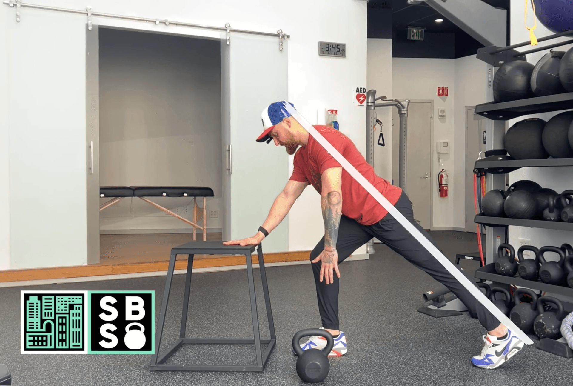 Person in a gym using a resistance band exercise with a kettlebell and workout equipment around.